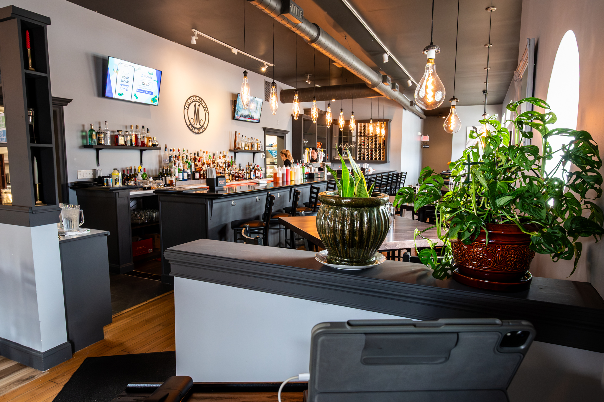 The Manhattan bar and lounge with Edison bulb lighting and lush plants